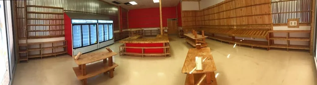 Wide view of a retail interior with custom-built wood tables, shelving, and a counter.