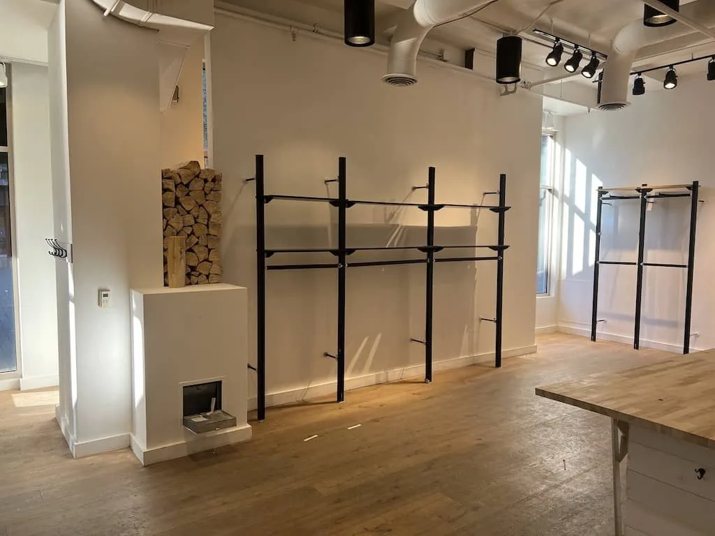 Retail space with black steel display racks and a wood counter installed against white walls.