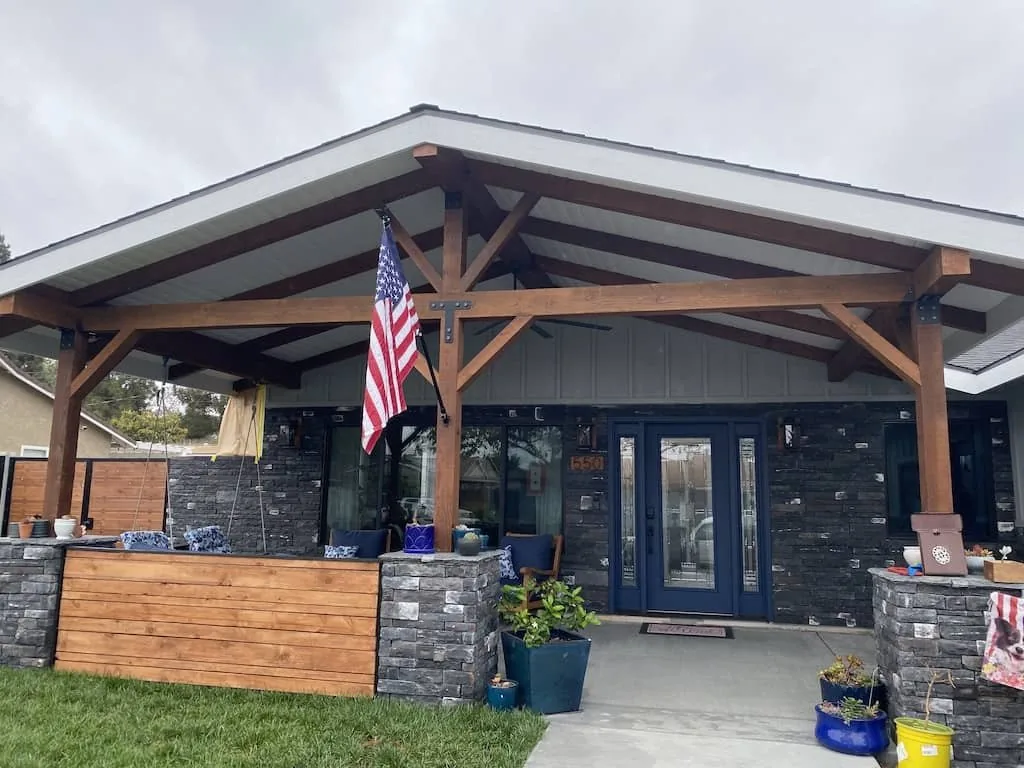 Finished front porch with heavy timber trusses and stacked stone columns, built by Tri Peak Construction & Design, Inc.